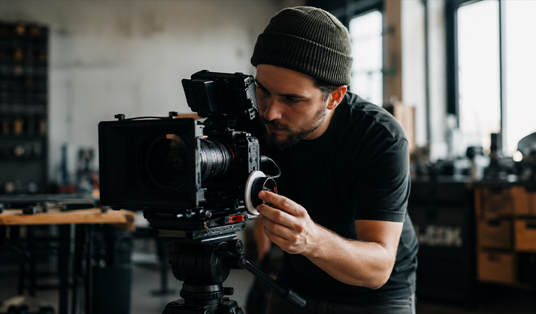 Filmskapare som ställer in fokus på en professionell systemkamera på stativ