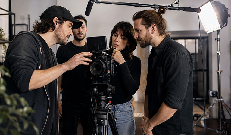 Filmteam som granskar kamerabilden under en inspelning med mikrofon och ljus